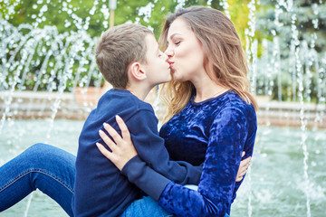 Happy beautiful mother and son enjoying near the fountain