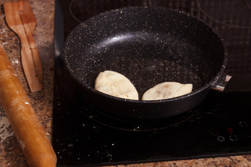 Meat pies, pan-fried in boiling oil. small raw pies in a frying pan with hot oil