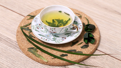 Зеленый чай в чашке с блюдцем с цветочным рисунком