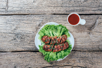Wooden board with grilled sausages on table