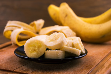 Sliced ripe banana in plate on wooden background.