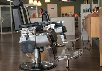 Sillas de peluquería vintage. Se ve la recepcionista al fondo y parte del salón.