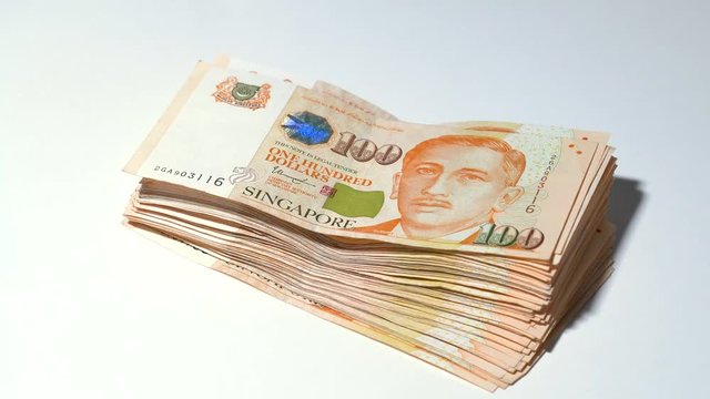 Panning in from the left to reveal a stack of SGD 100 dollar bill Singapore dollar currency