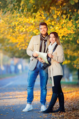 Young travel couple with map and camera in city autumn alley.