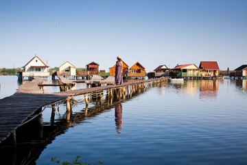 woman walking on the planks at floating village on lake Bokod, Hungary