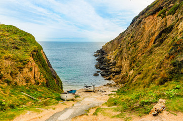 Amazing private beach on the coast of Cornwall, with a couple of boats moored on the shore.