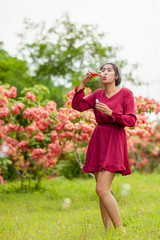 young asian woman with Carmen red dress blowing bubble