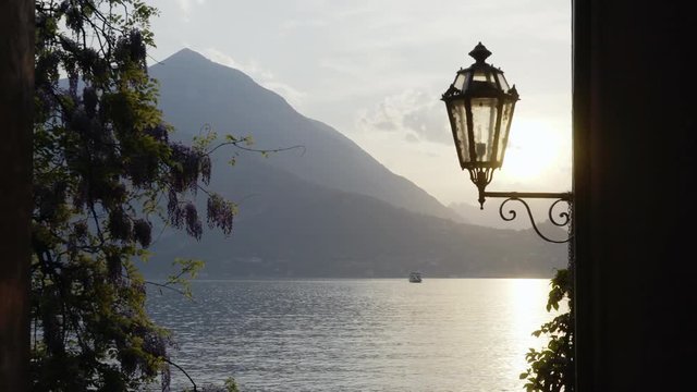 Landscape of Como lake. Sunset view through silhouette of vintage lantern and mountain at background