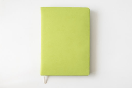 Top view of green cover notebook on white desk background with copy space