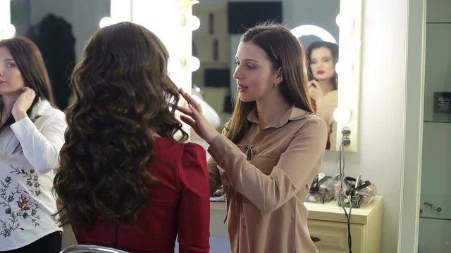 Make-up artist doing professional make-up for glamorous girls in a modern beauty salon.