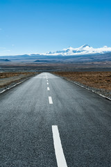 Naklejka premium Road leading toward snow mountain peak in the distance