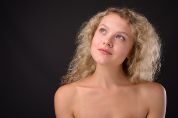Fototapeta premium Young beautiful woman with blond curly hair against gray backgro