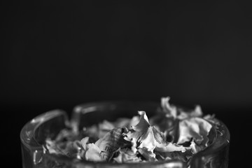 A piece of paper burning in a glass ashtray close up. Black and white