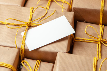 Pile Gift boxes in festive packaging with golden yellow bows and note or card. Delivery of gifts by the postal cargo service. Concept of New Year, birthday, valentine's day, holiday