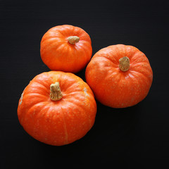 Halloween holiday minimal top view image of pumpkin over black wooden background.