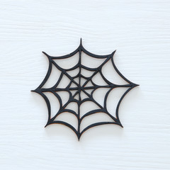 Halloween holiday minimal top view image of spider cobweb over white wooden background.