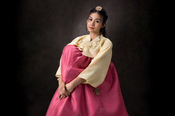 Beautiful Korean girl in Hanbok dress. Looks adorable and elegant. standing front of black background.