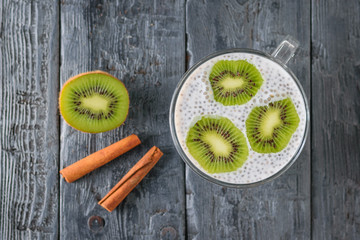 Two cinnamon sticks, Chia seed pudding with kiwi fruit on a dark wooden table. The view from the top. Flat lay.