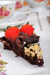 Piece of delicious homemade brownie cake with strawberries and tea set on white table. Selective focus