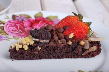 Piece of delicious homemade brownie cake with strawberries and tea set on white table. Selective focus