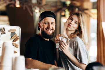 Two young smiling people.dressed in casual outfit, stand next to each other and smile to the camera in a cozy coffee shop.