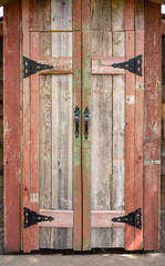 Wooden doors of plank house with black metal handles and hinges