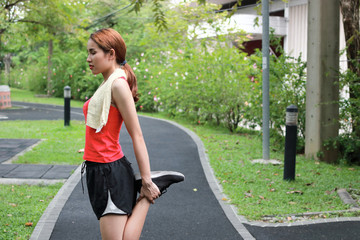 Fototapeta premium Healthy Asian woman stretching her legs before run in park. Fitness and exercise concept.