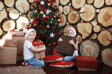Two brother boys around a Christmas tree.
