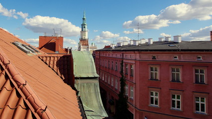 Ratuszowa wieża na poznańskim rynku widziana z nad dachów starych, czerwonych kamienic starego...
