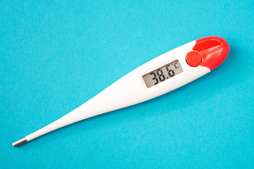 White digital clinical thermometer on blue background shows fever heat temperature