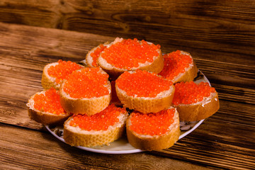 Sandwiches with red caviar on wooden table