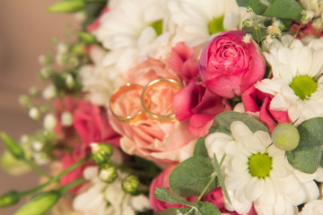 Close-up wedding rings on the natural roses bouquet