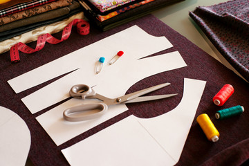 The process of sewing clothes. Pattern, fabric, tailoring scissors, tape measure, thread for sewing fashionable clothes. The process of sewing dresses using patterns.