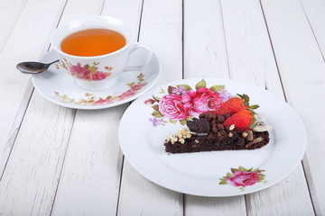 Piece of delicious homemade brownie cake with strawberries and tea  on white table. Selective focus