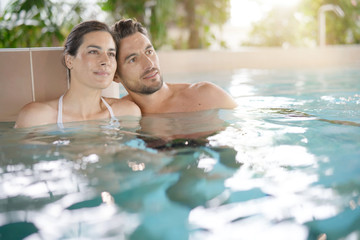 Couple relaxing in spa resort pool - obrazy, fototapety, plakaty