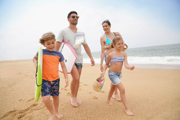 Family of 4 walking on sandy beach, ocean view