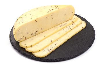Sliced Cheese with cumin seeds on a slate shale plate, isolated on a white background.
