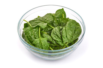Green spinach leaves in a glass bowl, isolated on a white background.
