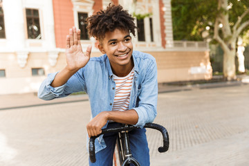 Smiling young african man outdoors, riding on a bicycle