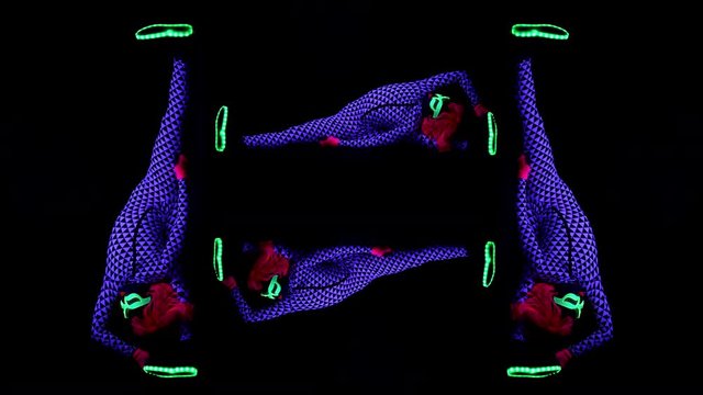 amazing female yoga instructor moving between poses wearing fluorescent clothing under UV black light made into an interesting pattern