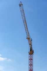 Crane on a construction site against a blue sky.