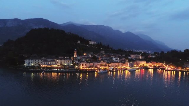 Aerial view illuminated town placed on cape lanterns light reflecting in water motion panoram along city over lake. Bellagio, Italy