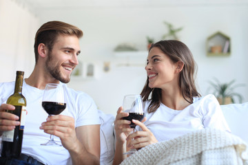 Young loving couple drinking a glass of red wine in their living room.