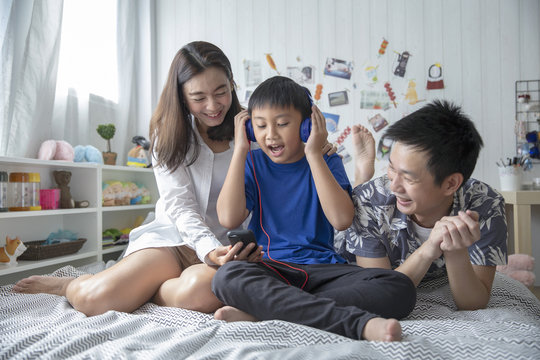 Happy family while using a smartphone listen to music and smiling enjoy spending time together at home