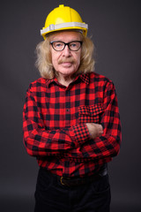 Senior man construction worker against gray background