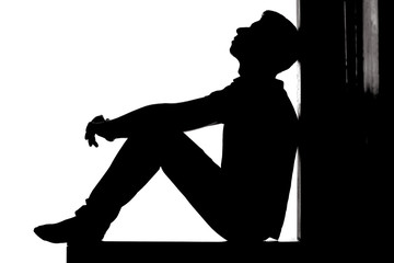 Profile of a young pensive man sitting on the floor and looking up with hope and despair, guy in...