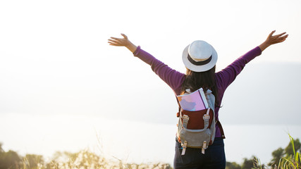 traveler woman standing with raised arms  on peak mountain.