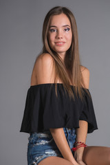 Young beautiful woman teenager in a black top and torn denim shorts