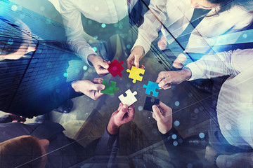Business people join puzzle pieces in office. Concept of teamwork and partnership. double exposure with light effects
