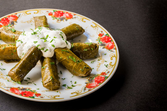 Stuffed grape leaves with meat and rice served with yogurt on a plate called dolmadakia or dolma. Traditional turkish and greek cuisine 